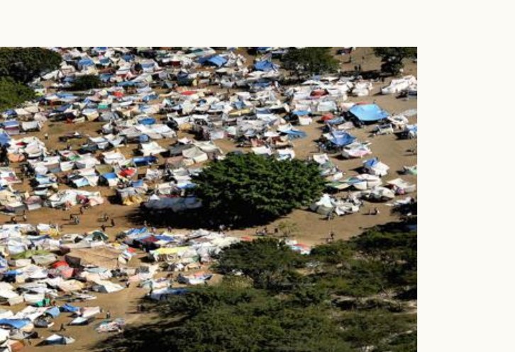 A sprawling refugee camp of improvised tents spreading among sparse trees