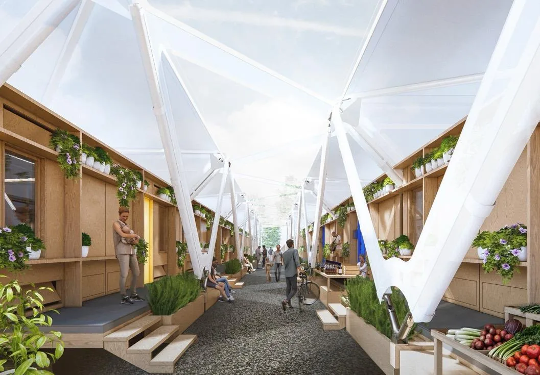 A covered market street between assembled Estia Homes, with produce stalls, planting, and residents at work, a local economy taking root